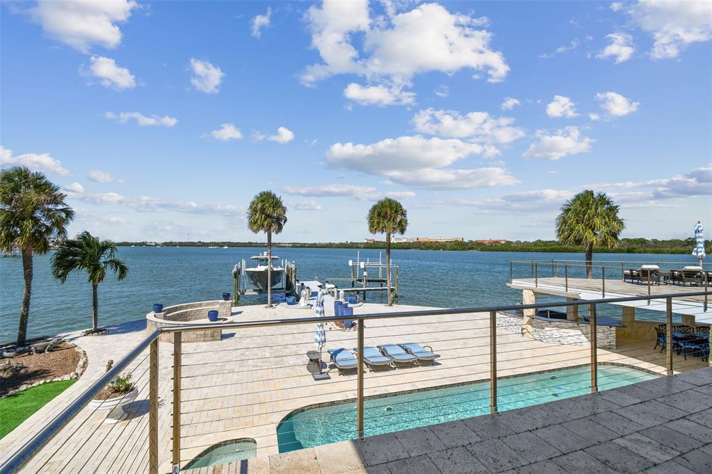 A waterfront patio features a swimming pool, lounge chairs, a boat dock, and palm trees — 582 JOHNS PASS AVENUE, MADEIRA BEACH, FL