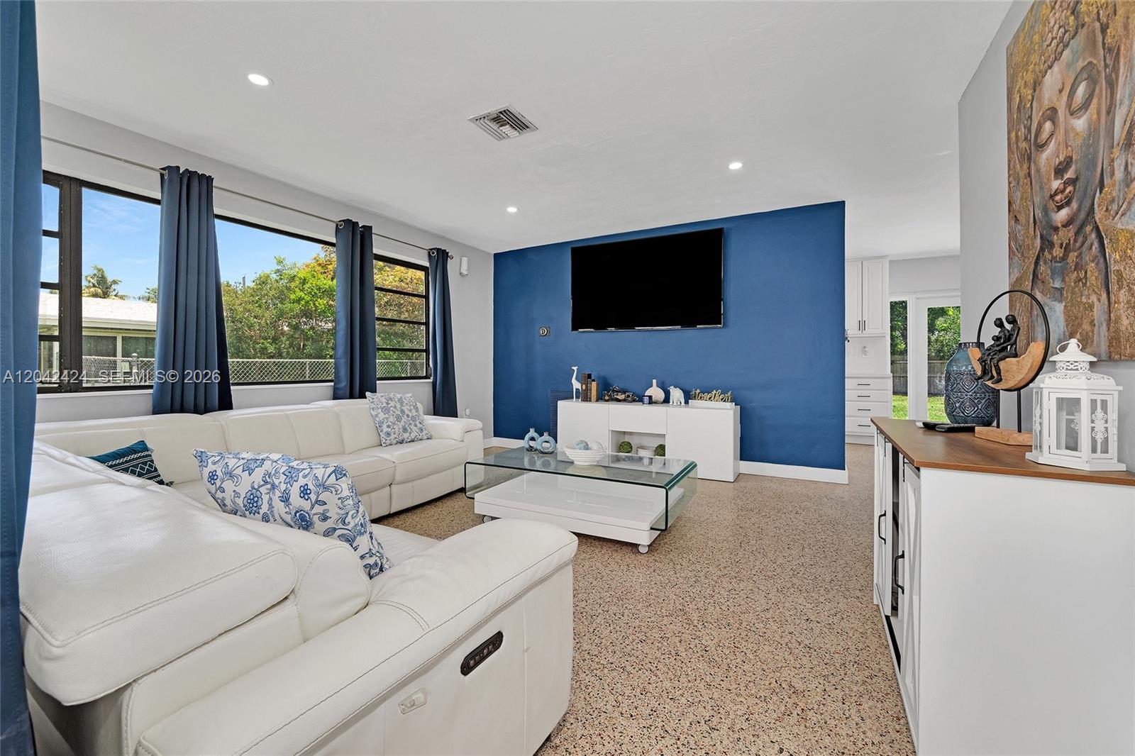 A living room features a white sectional sofa, a blue accent wall, and terrazzo flooring — 19601 Belview Dr, Cutler Bay FL 33157, CUTLER BAY, FL