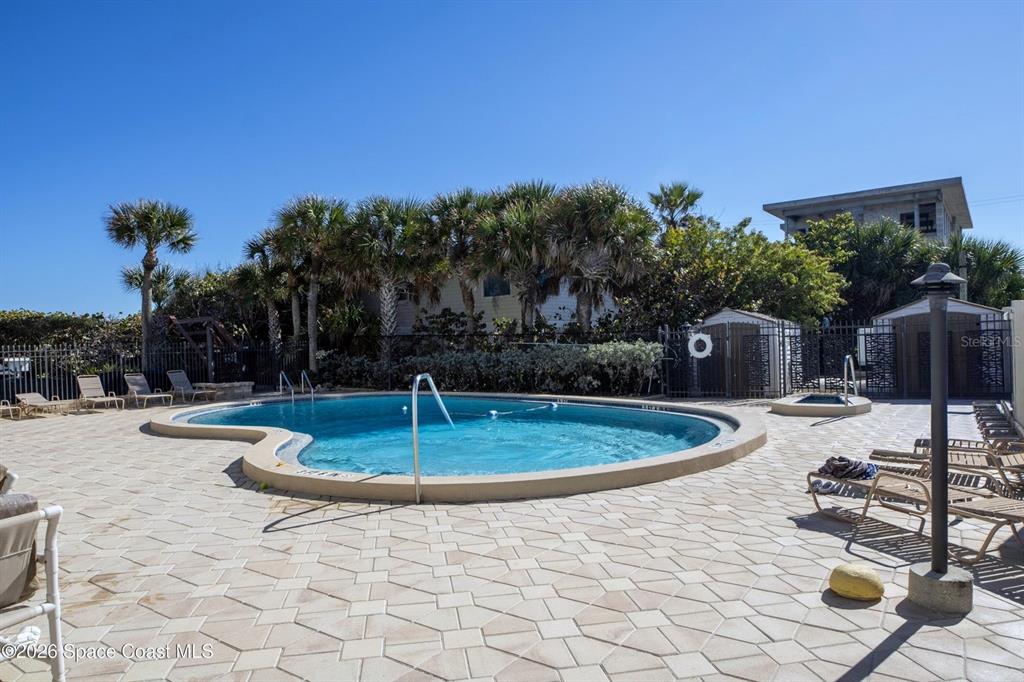 An outdoor swimming pool with a surrounding paved deck and lounge chairs — 2815 S ATLANTIC AVENUE UNIT 705, COCOA BEACH, FL