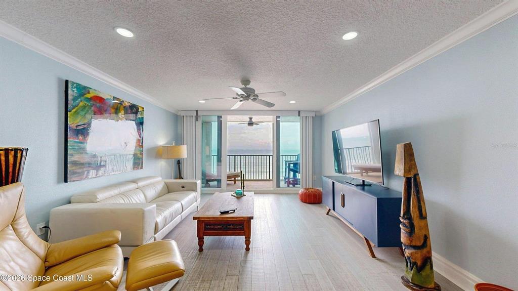 A living room features a white sofa, wood coffee table, and a balcony overlooking the ocean — 2815 S ATLANTIC AVENUE UNIT 705, COCOA BEACH, FL