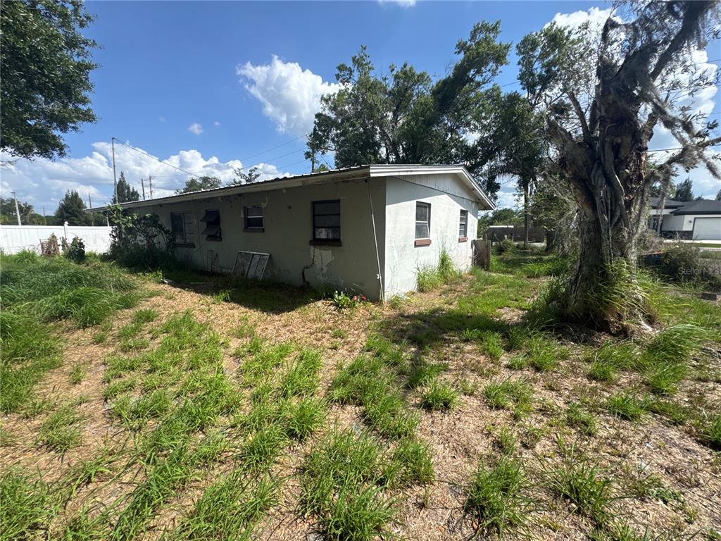 The exterior of a single-story house with a concrete block wall and overgrown grass — 2152 SE CARLSTROM FIELD ROAD, ARCADIA, FL