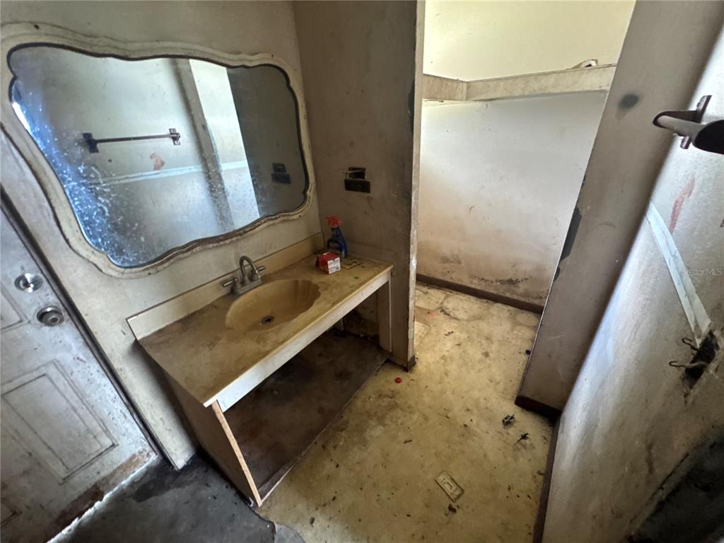 A bathroom with a vanity, sink, mirror, and unfinished walls in need of renovation — 2152 SE CARLSTROM FIELD ROAD, ARCADIA, FL