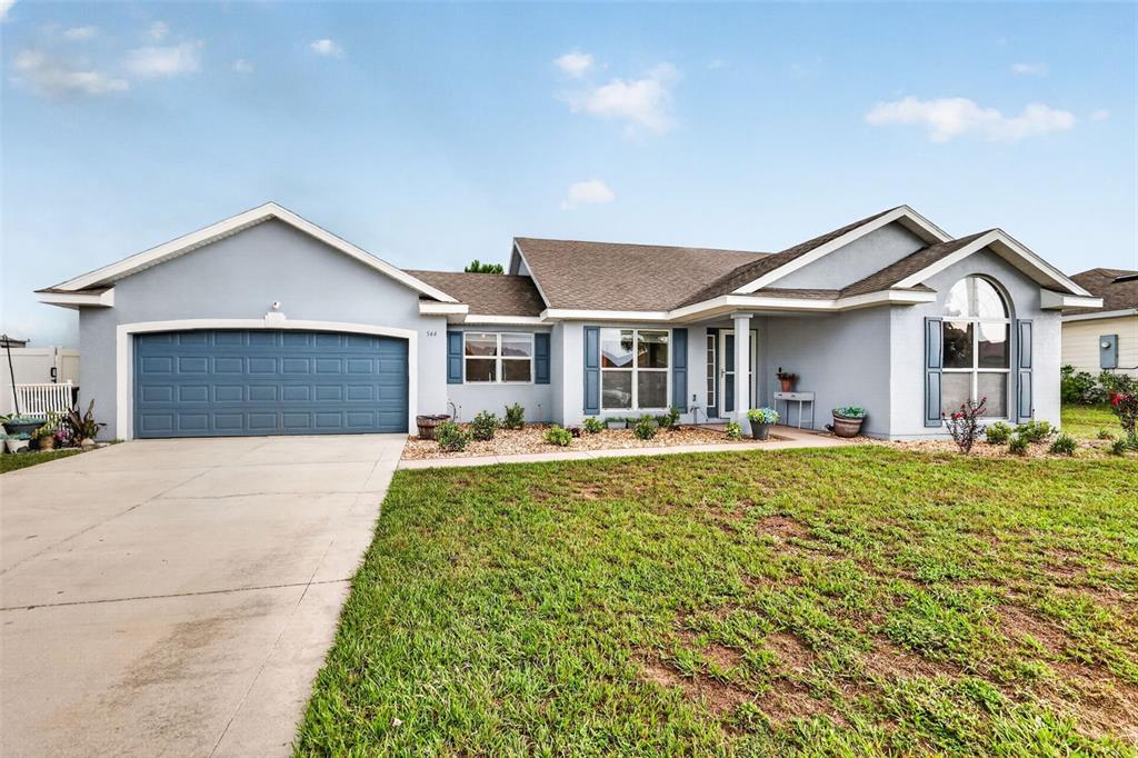A single-story house with a blue garage door, light blue siding, and a front lawn — 544 TORTOLA AVENUE, TAVARES, FL