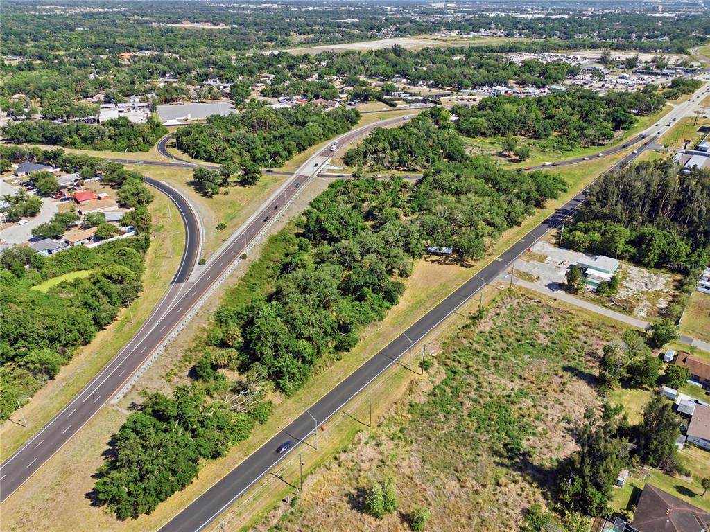 An aerial view shows a highway intersection surrounded by trees, grassy fields, and residential areas — 4340 US 19, PALMETTO, FL