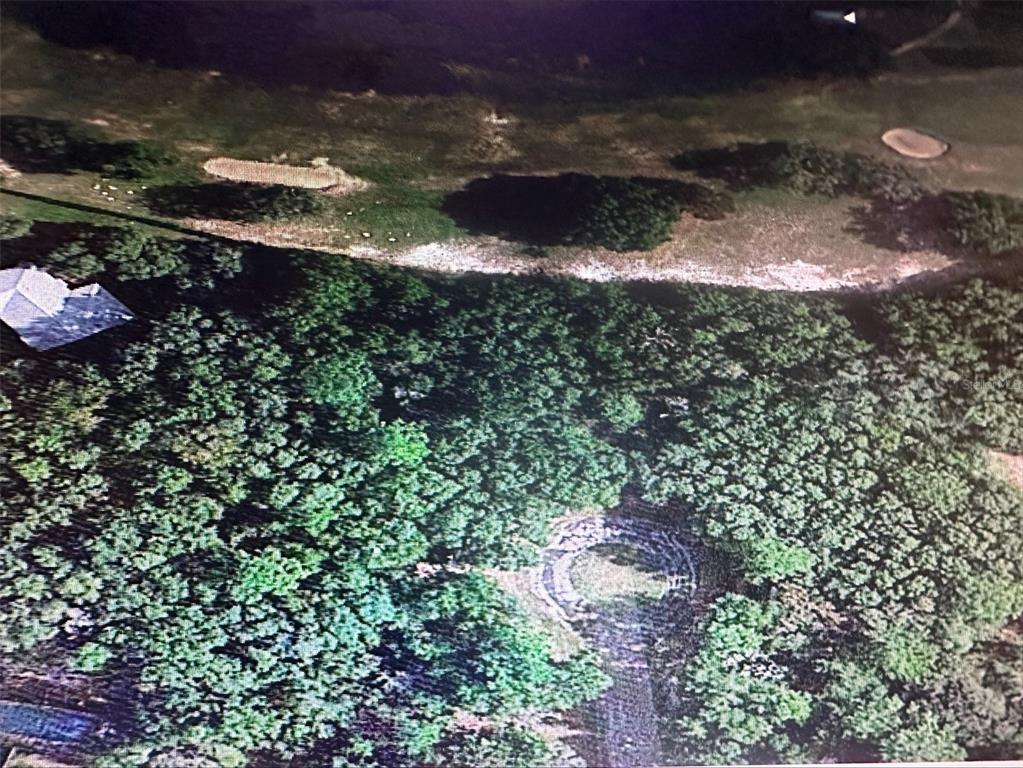 An aerial view shows a wooded lot adjacent to a golf course with sand traps — 2981 W CHALLENGE COURT, CITRUS SPRINGS, FL