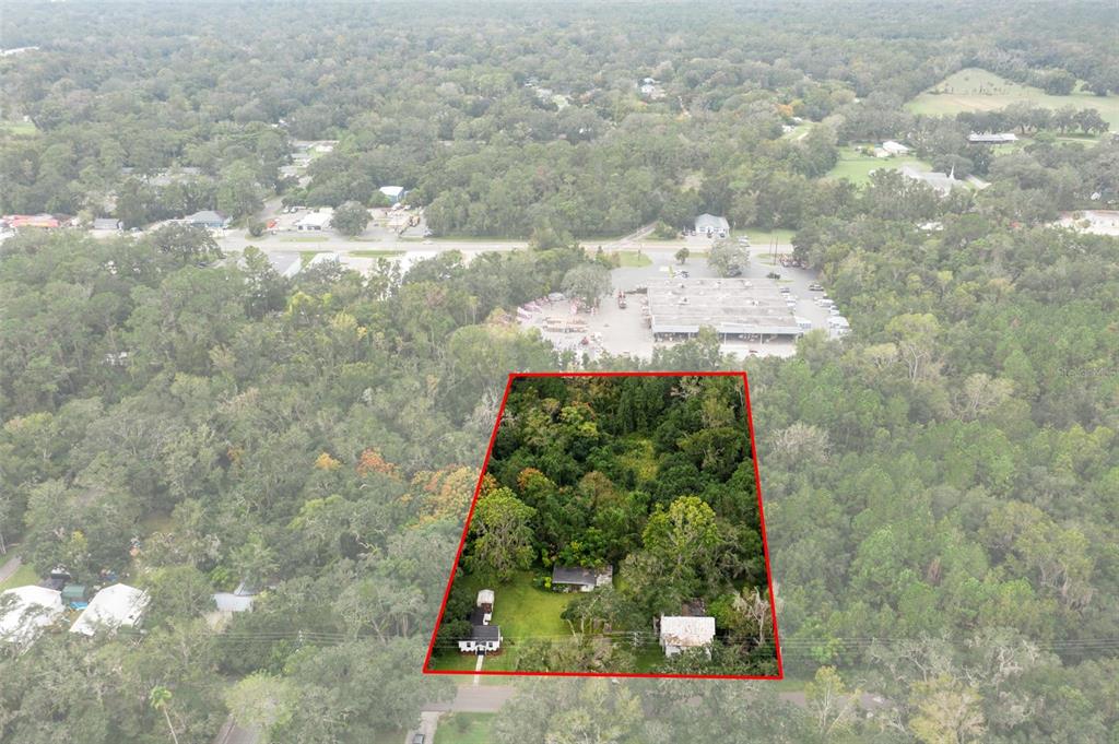 An aerial view shows a wooded lot with two small buildings outlined in red — 515 STAFFORD AVENUE, BROOKSVILLE, FL