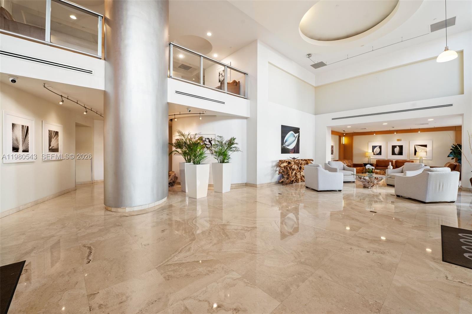 A spacious, high-ceilinged lobby features polished marble floors, a large silver column, and seating areas — 2080 S Ocean Dr # 1402, Hallandale Beach FL 33009, HALLANDALE BEACH, FL