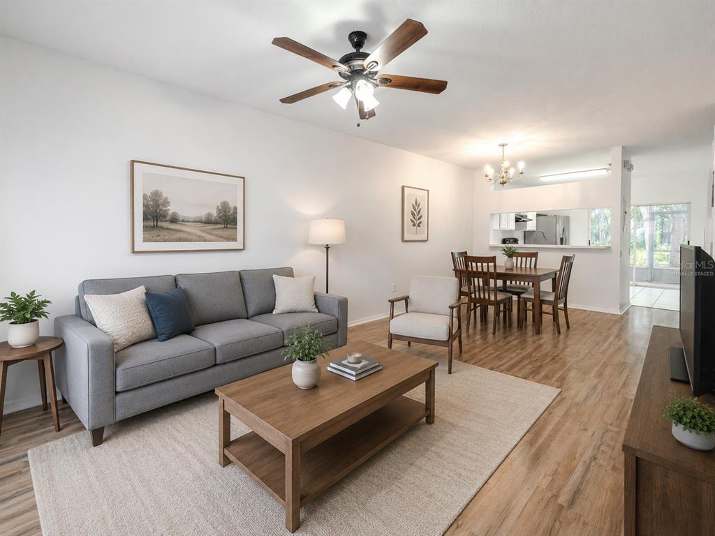 A living room with a gray sofa, wood coffee table, and an adjacent dining area — 2432 LAKE WOODBERRY CIRCLE, BRANDON, FL