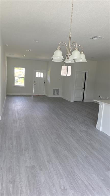 An open-concept living area features light gray wood-look flooring and a hanging chandelier — 2500 SW 156TH LANE ROAD, OCALA, FL