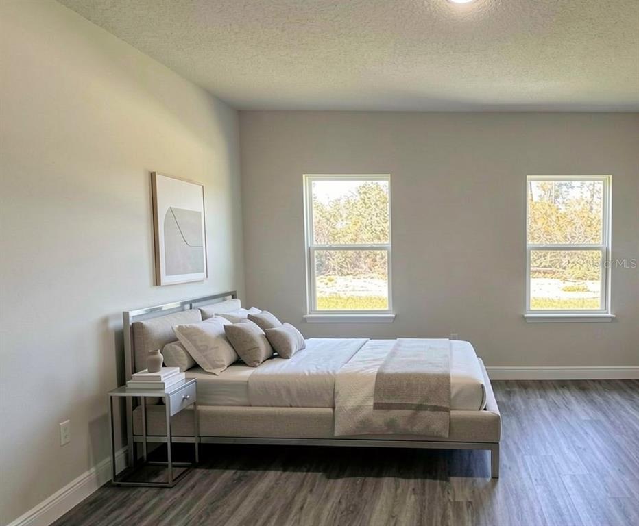 A bedroom with light gray walls, wood-look flooring, a platform bed, and two windows — 2500 SW 156TH LANE ROAD, OCALA, FL