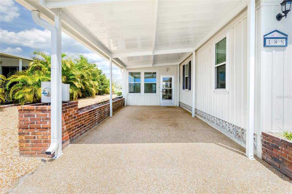 A covered carport with a textured concrete floor sits beside a light-colored mobile home — 18 S DE LAS PALMAS STREET, ENGLEWOOD, FL
