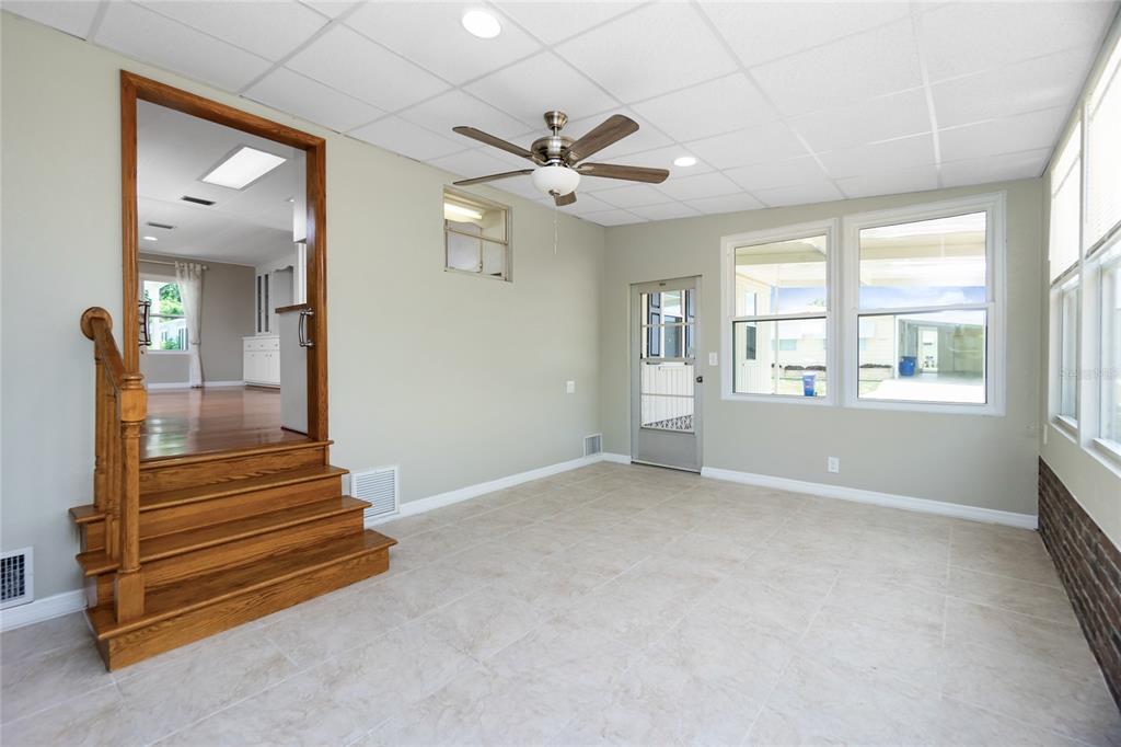 A sunroom with tile flooring, a ceiling fan, and wooden stairs leading to another room — 18 S DE LAS PALMAS STREET, ENGLEWOOD, FL