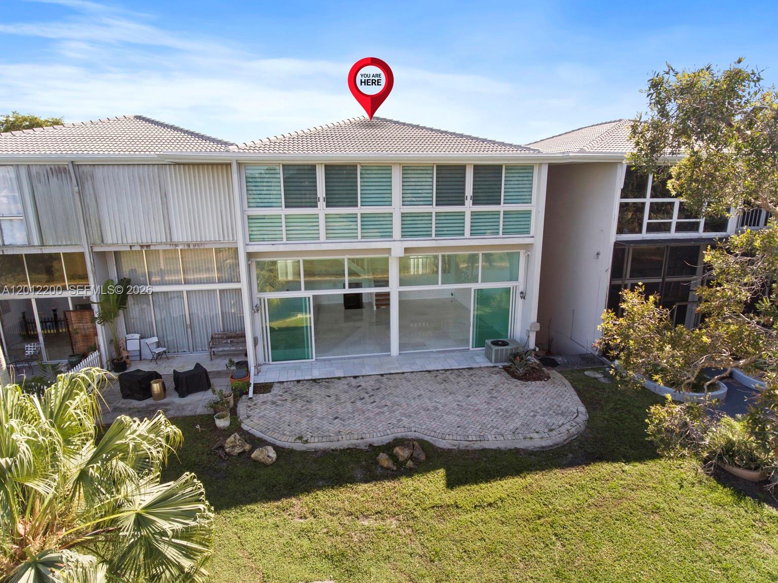 An exterior view of a multi-story townhouse with a paved patio and large windows — 6795 Brookline Dr # 6795, Miami FL 33015, MIAMI, FL