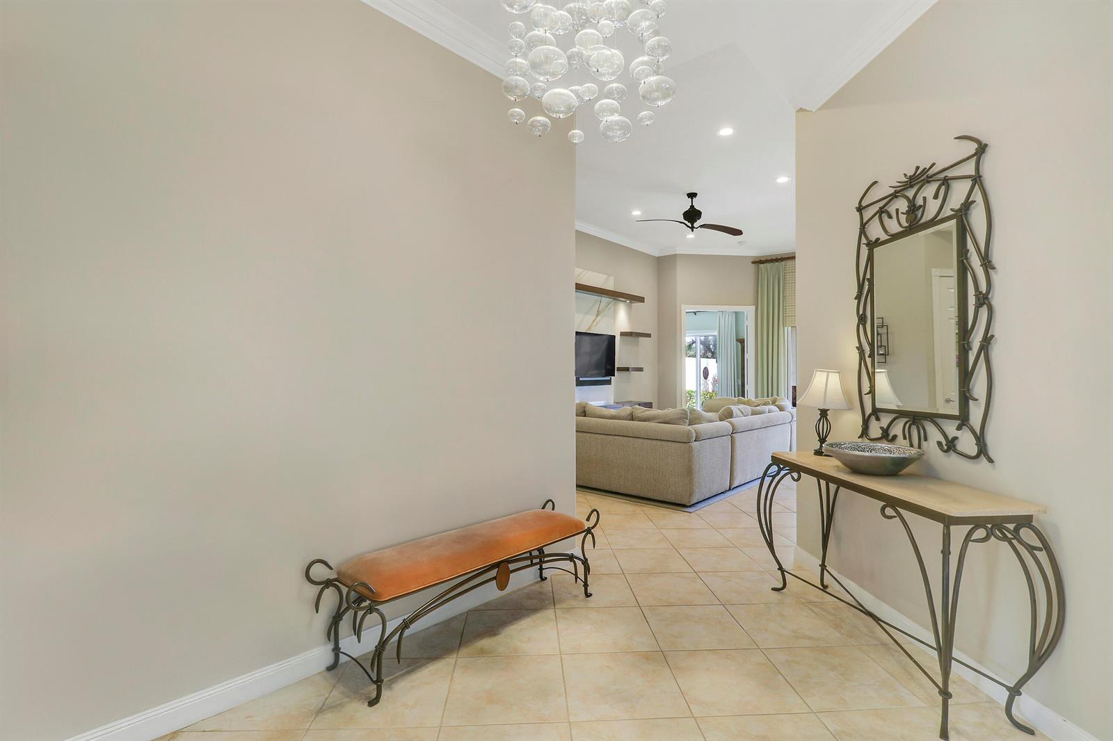 A foyer with a bench and console table leads into a living room with tile floors — 8435 Belize Place, Wellington FL 33414, WELLINGTON, FL