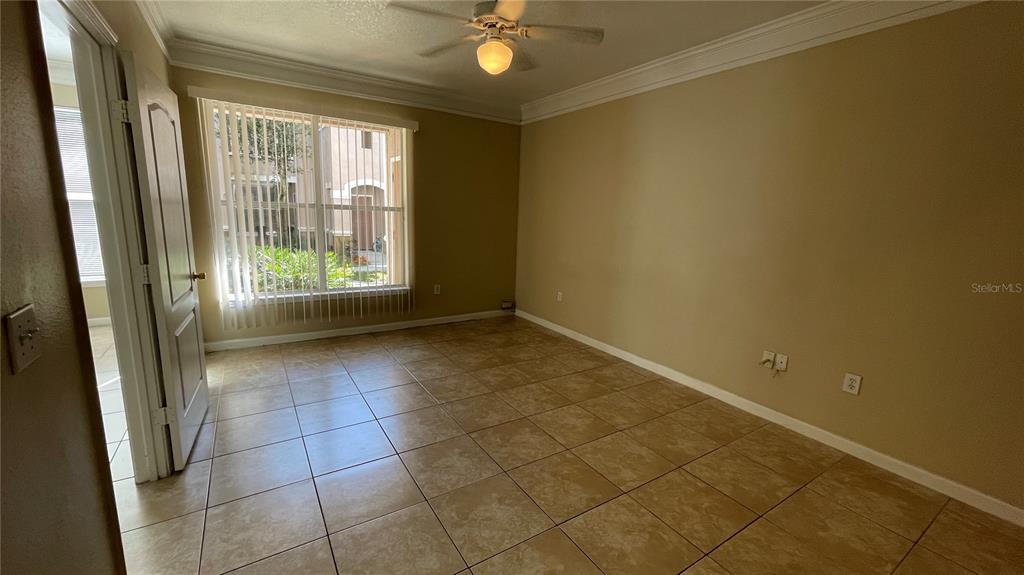 An empty bedroom features tan walls, tile flooring, a ceiling fan, and a large window — 17954 VILLA CREEK DRIVE UNIT 17954, TAMPA, FL