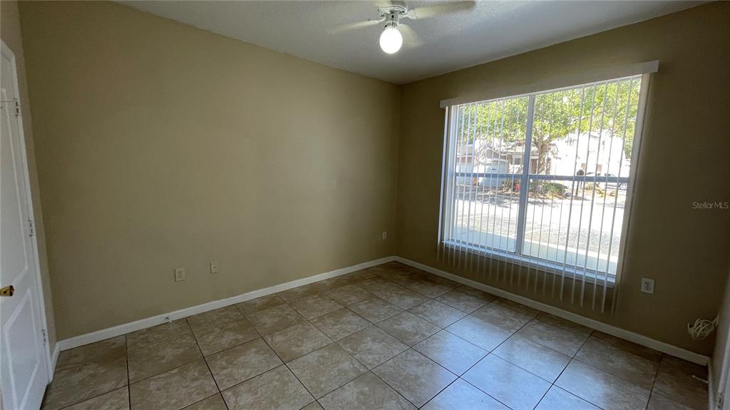 An empty bedroom features beige walls, tile flooring, a ceiling fan, and a large window — 17954 VILLA CREEK DRIVE UNIT 17954, TAMPA, FL