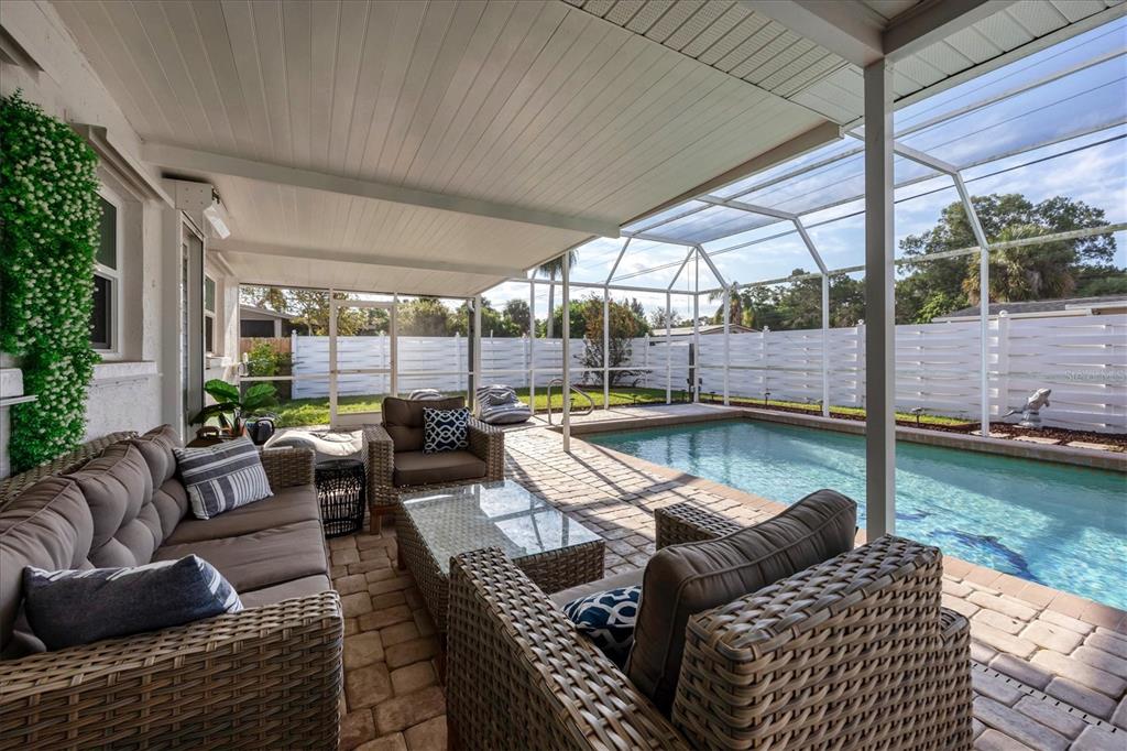 A covered patio with wicker furniture overlooks a screened-in swimming pool and a white fence — 3126 BOUGAINVILLEA STREET, SARASOTA, FL