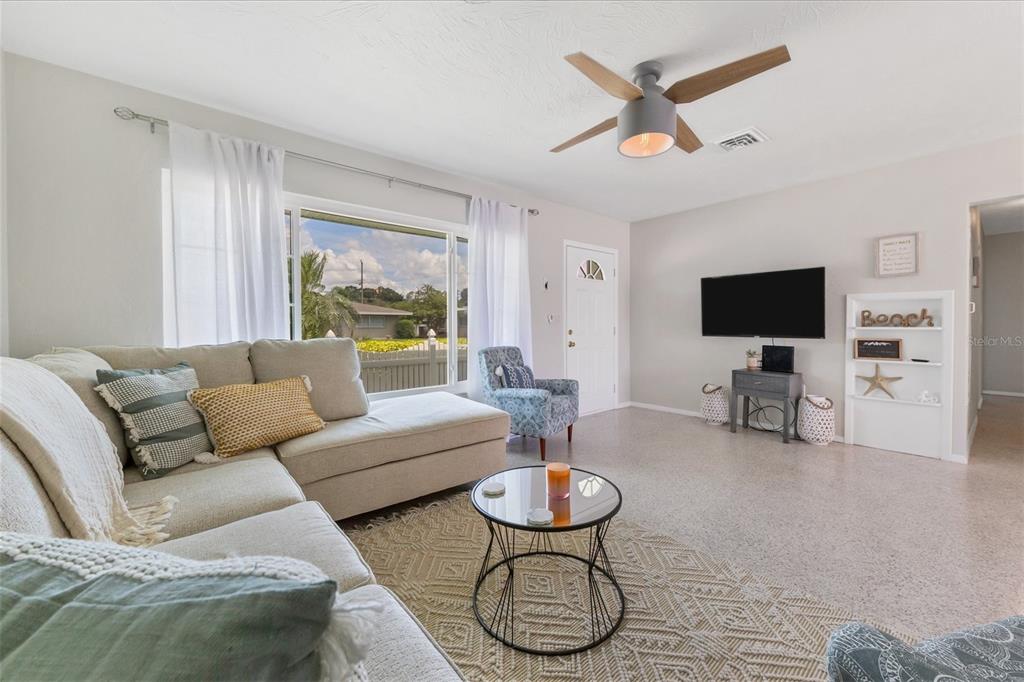 A living room features a sectional sofa, a glass coffee table, and a wall-mounted television — 3126 BOUGAINVILLEA STREET, SARASOTA, FL