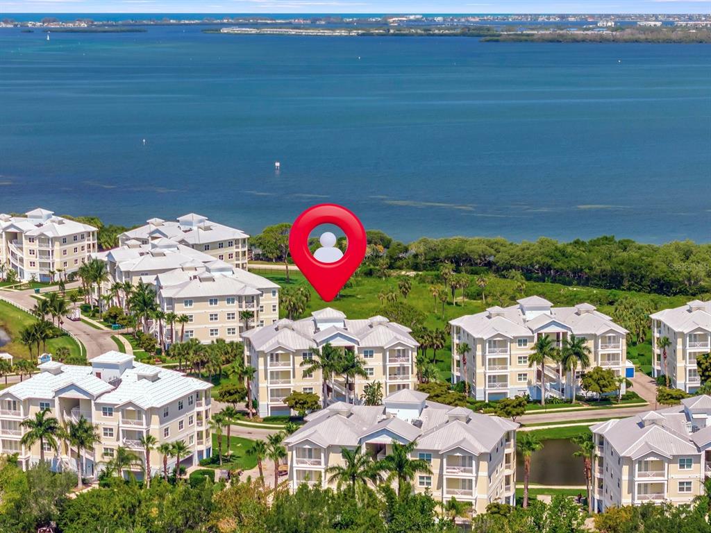 An aerial view shows multi-story residential buildings near a large body of water — 7840 34TH AVENUE W UNIT 202, BRADENTON, FL