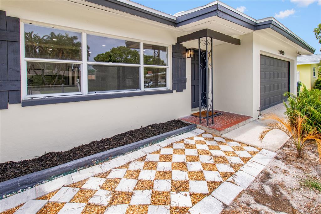 The exterior of a house features a checkered walkway, a garage, and a covered entryway — 12120 CROFT DRIVE, LARGO, FL