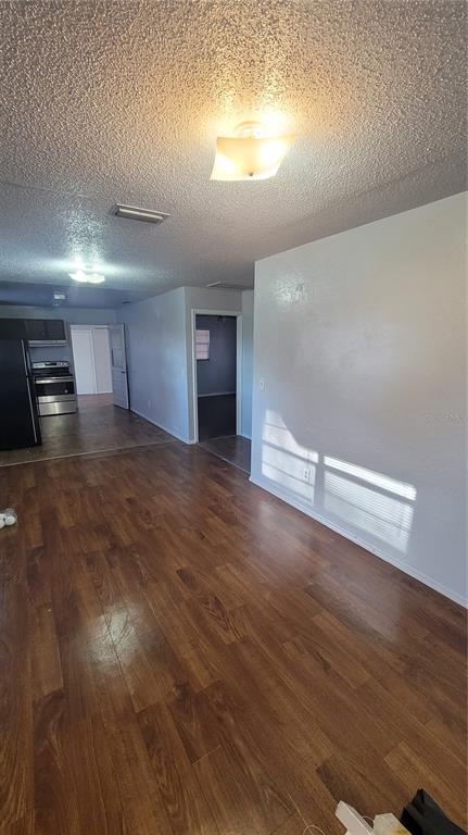 A living area with wood-look flooring leads to a kitchen and a hallway — 883 W OHIO AVENUE, LAKE HELEN, FL