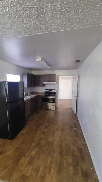 A kitchen with dark wood cabinets, stainless steel appliances, and wood-look flooring — 883 W OHIO AVENUE, LAKE HELEN, FL