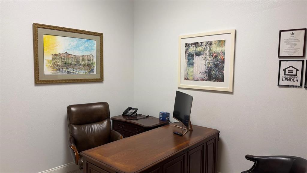 A home office features a wooden desk, a leather chair, and framed wall art — 7901 KINGSPOINTE PARKWAY UNIT 8, ORLANDO, FL
