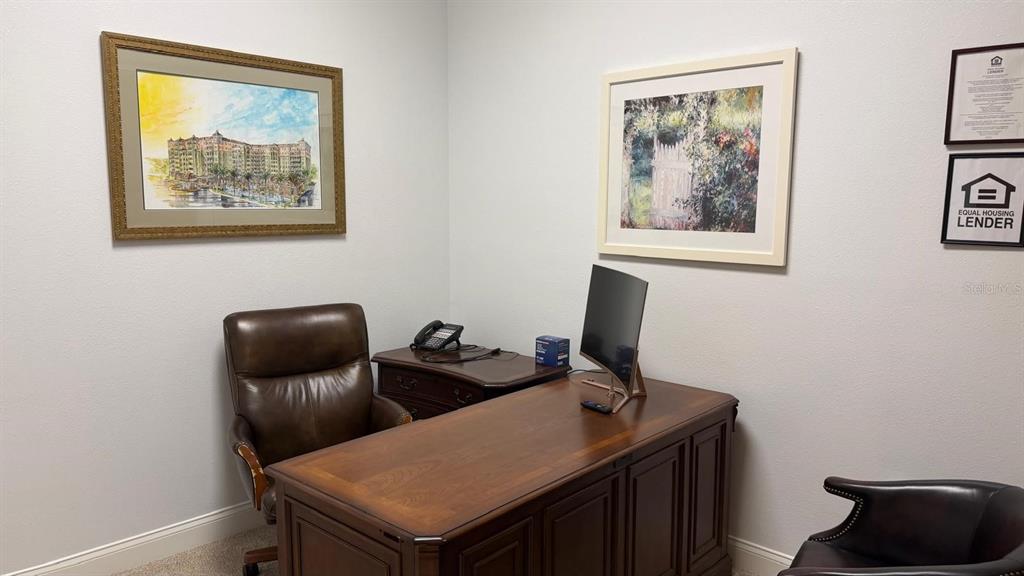 A home office features a wooden desk, a leather chair, and two framed pictures on walls — 7901 KINGSPOINTE PARKWAY UNIT 8, ORLANDO, FL