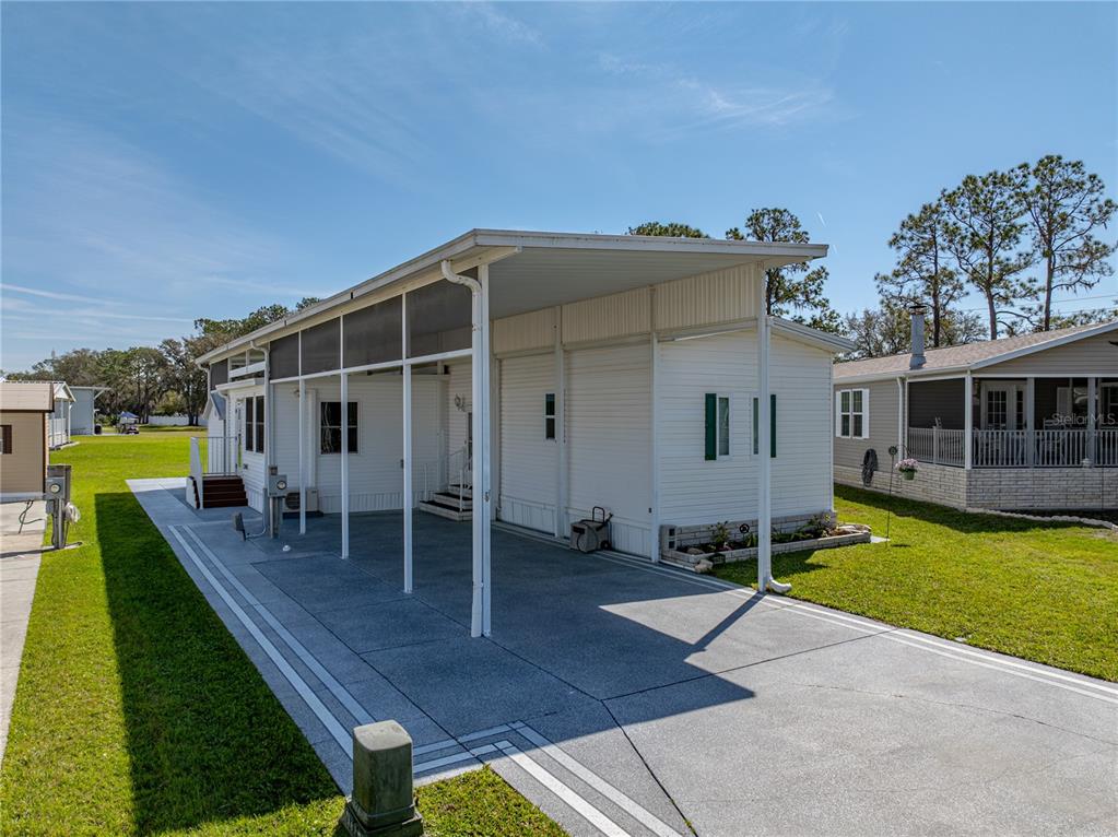 A white mobile home features a large attached carport and a concrete driveway — 8925 SOUTHSHORE COURT, POLK CITY, FL