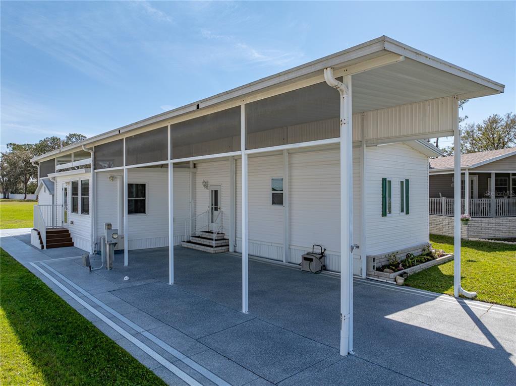 A white mobile home features a large carport and a screened-in patio area — 8925 SOUTHSHORE COURT, POLK CITY, FL