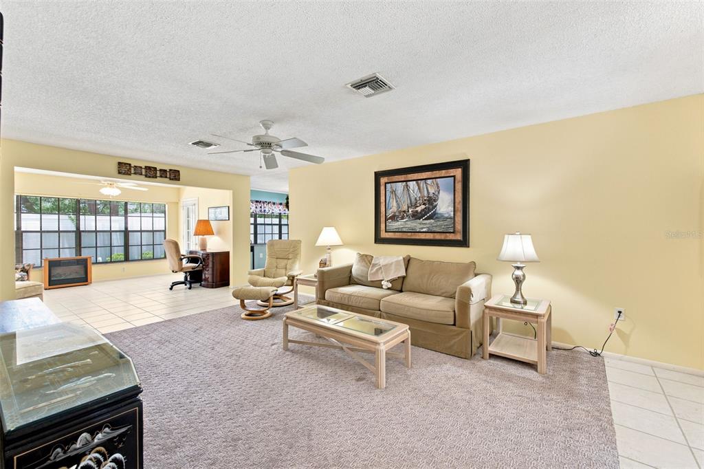 A living room features a beige sofa, a glass-top coffee table, and a recliner — 6695 PIN OAK COURT, SPRING HILL, FL