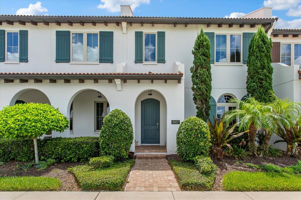 A two-story townhouse with a white stucco facade, green shutters, and a brick walkway — 8937 LAKESHORE POINTE DRIVE, WINTER GARDEN, FL