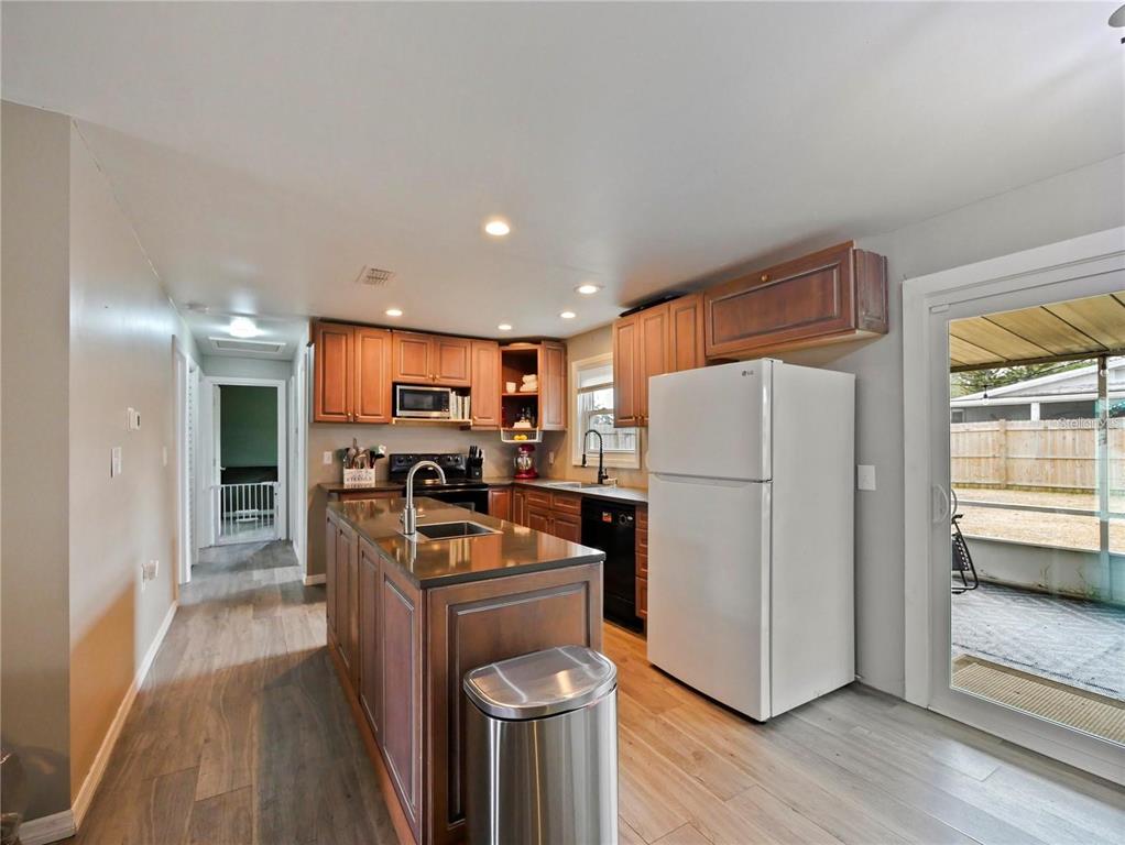 A kitchen with wood cabinets, a center island, stainless steel appliances, and wood-look flooring — 53 HIGHRIDGE ROAD, DAYTONA BEACH, FL