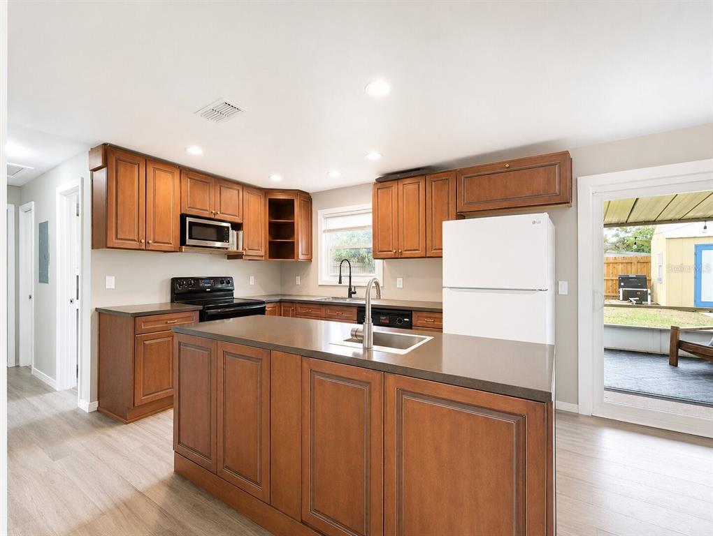 A kitchen with wood cabinets, a central island, dark countertops, and a white refrigerator — 53 HIGHRIDGE ROAD, DAYTONA BEACH, FL