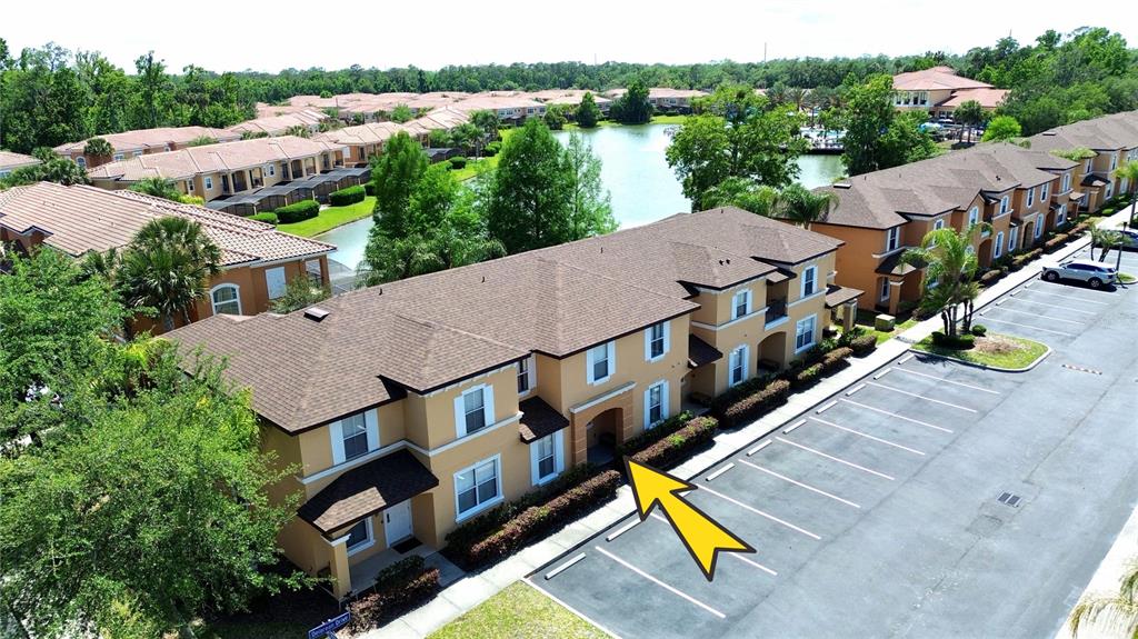 An aerial view of a multi-story apartment building with a parking lot and a lake — 5702 DELOREAN DRIVE, KISSIMMEE, FL
