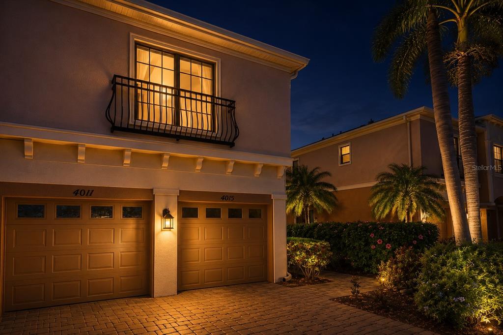 Exterior view of a two-story house at night with two garage doors and a balcony — 4015 OVERTURE CIRCLE UNIT 312, BRADENTON, FL