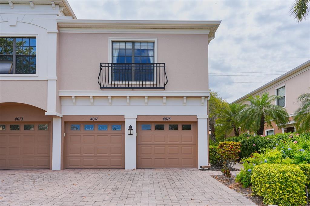 A two-story townhouse exterior features a paved driveway, two garage doors, and a small balcony — 4015 OVERTURE CIRCLE UNIT 312, BRADENTON, FL