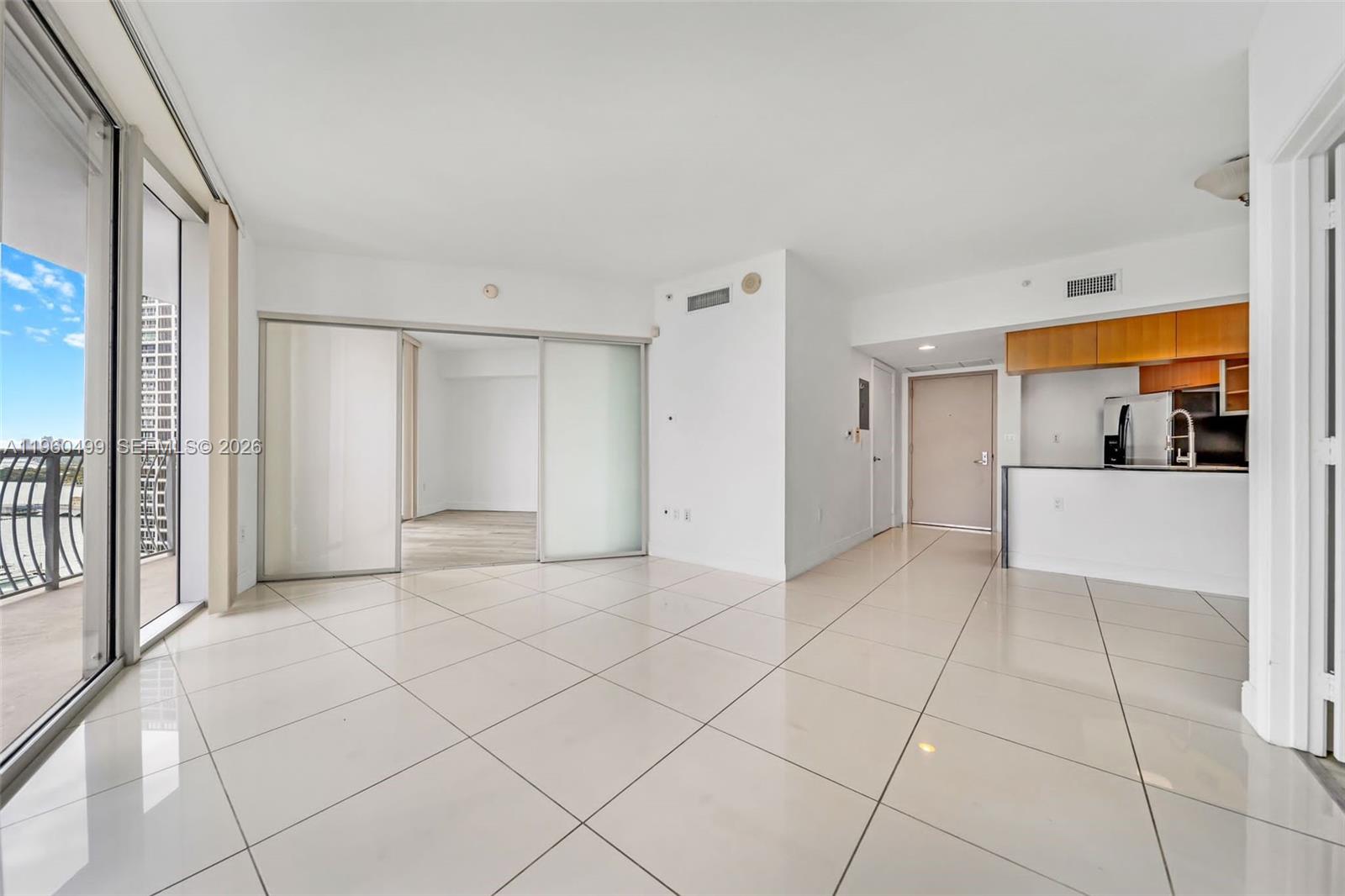 An open-concept living area features white tile floors, sliding glass doors, and a small kitchen — 1750 N Bayshore Dr # 2001, Miami FL 33132, MIAMI, FL