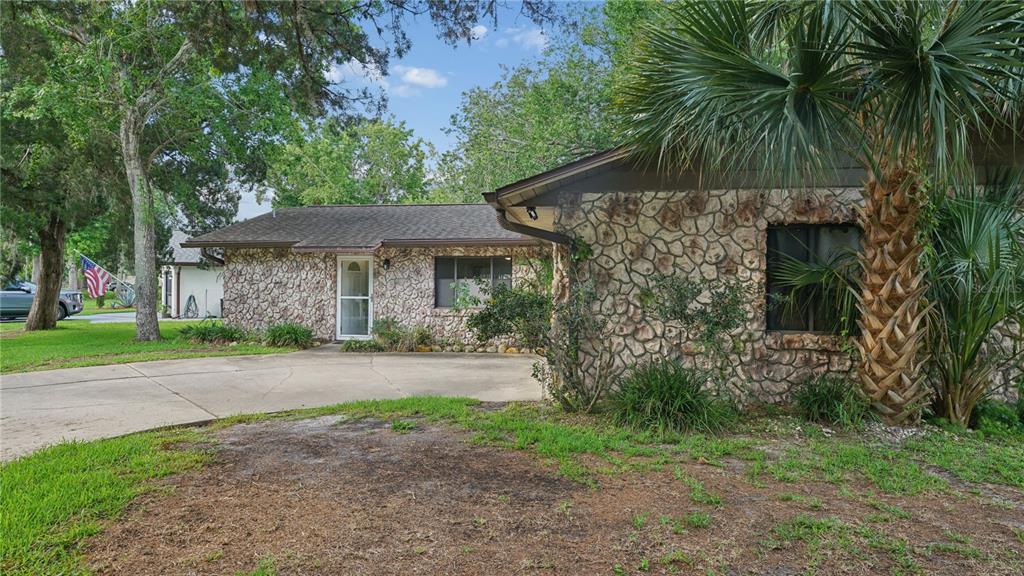 A single-story house with a stone facade and a concrete driveway surrounded by trees — 1968 RED CEDAR CIRCLE, SOUTH DAYTONA, FL