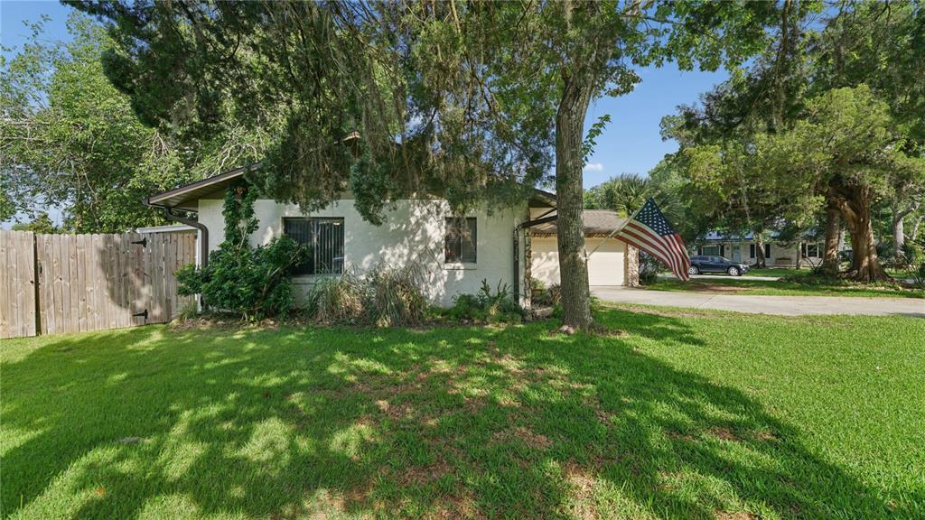 A single-story house with a white stucco exterior, a wooden fence, and an American flag — 1968 RED CEDAR CIRCLE, SOUTH DAYTONA, FL