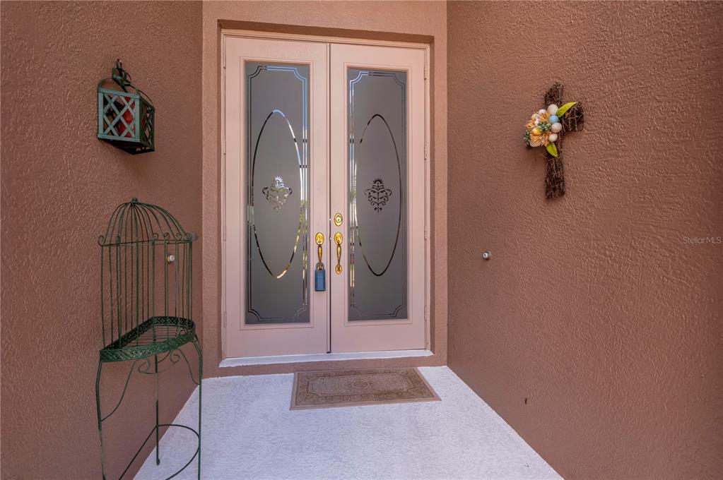 A front entryway features double glass-paneled doors, a decorative birdcage, and a wall-mounted cross — 10488 PRINCESS COURT, PUNTA GORDA, FL