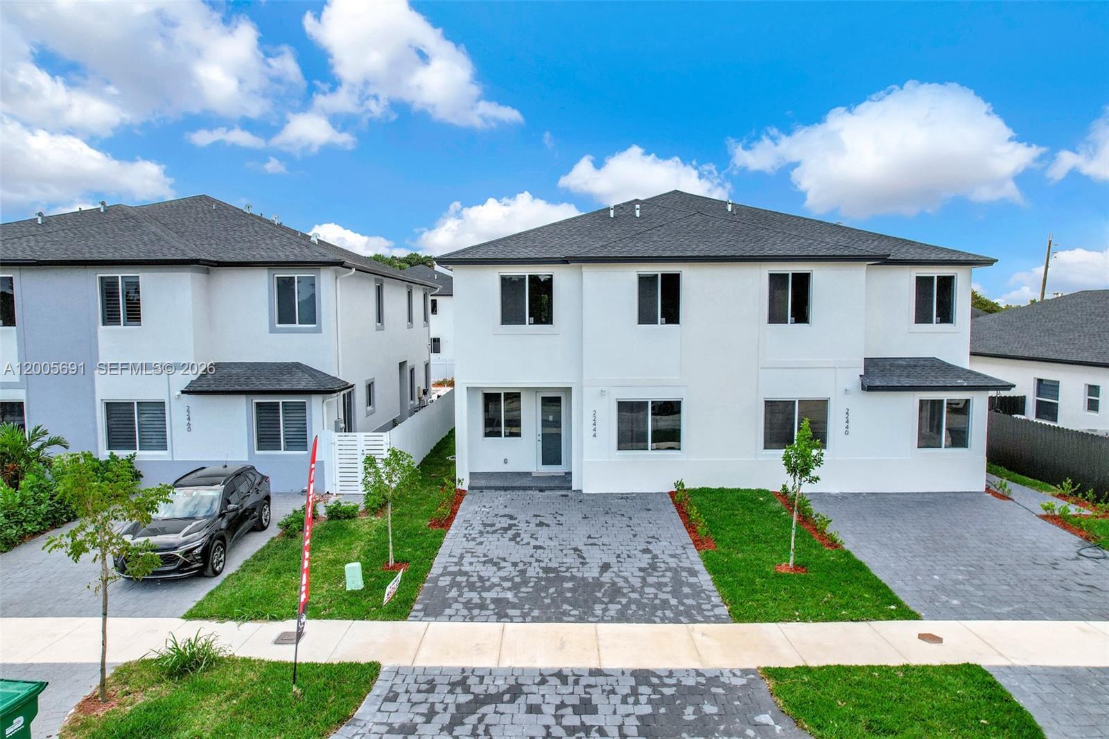 An exterior view shows two modern two-story white townhouses with paved driveways and green lawns — 22555 SW 125th Ave, Miami FL 33170, MIAMI, FL
