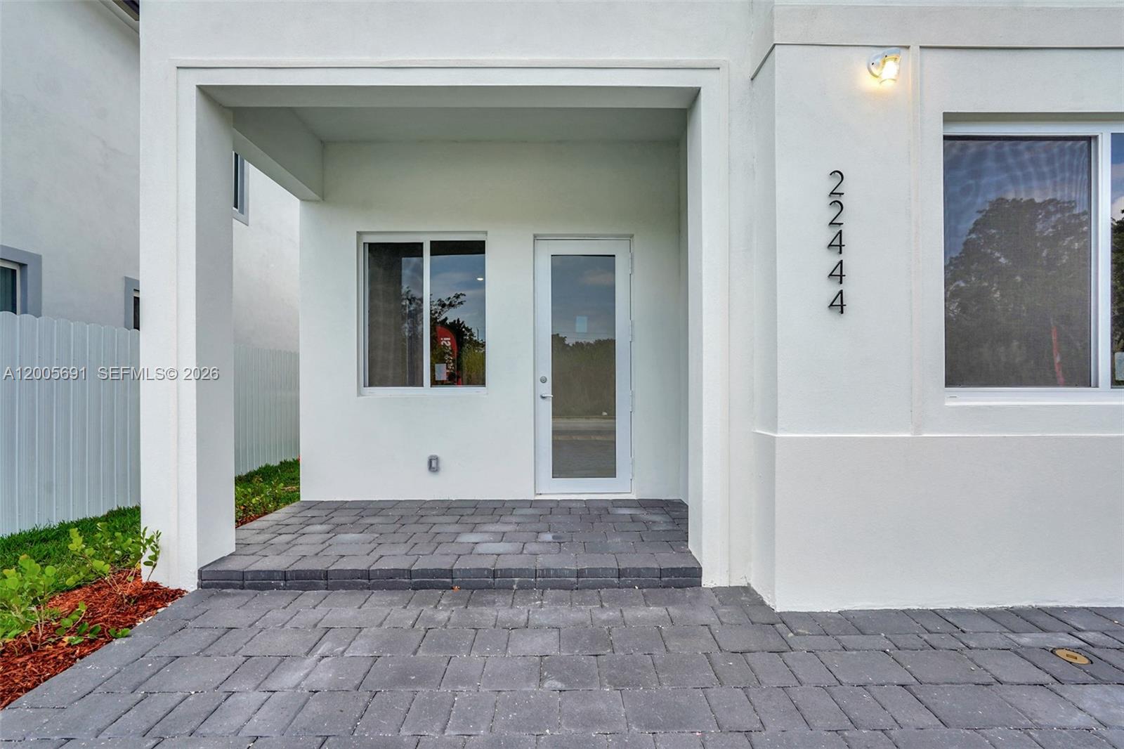 A white exterior wall features a glass door, a window, and a paved entryway — 22555 SW 125th Ave, Miami FL 33170, MIAMI, FL