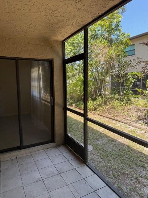 A screened-in patio with tiled flooring and a sliding glass door leading to the interior — 7273 CLOISTER DRIVE UNIT 121, SARASOTA, FL