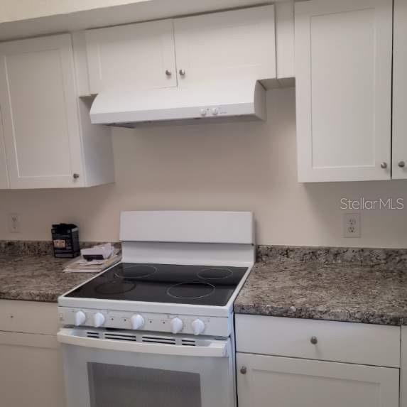 A kitchen features white cabinets, a white electric stove, and speckled granite countertops — 7273 CLOISTER DRIVE UNIT 121, SARASOTA, FL