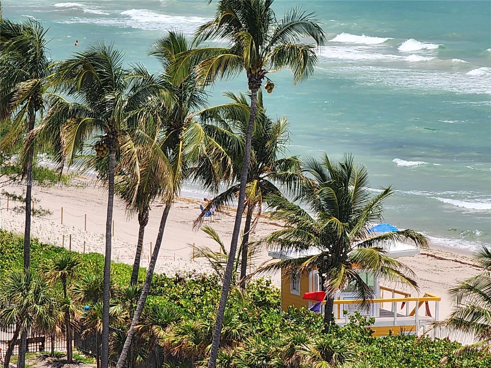 An elevated view of a sandy beach with palm trees and a lifeguard station — 2030 S Ocean Dr # 923, Hallandale Beach FL 33009, HALLANDALE BEACH, FL