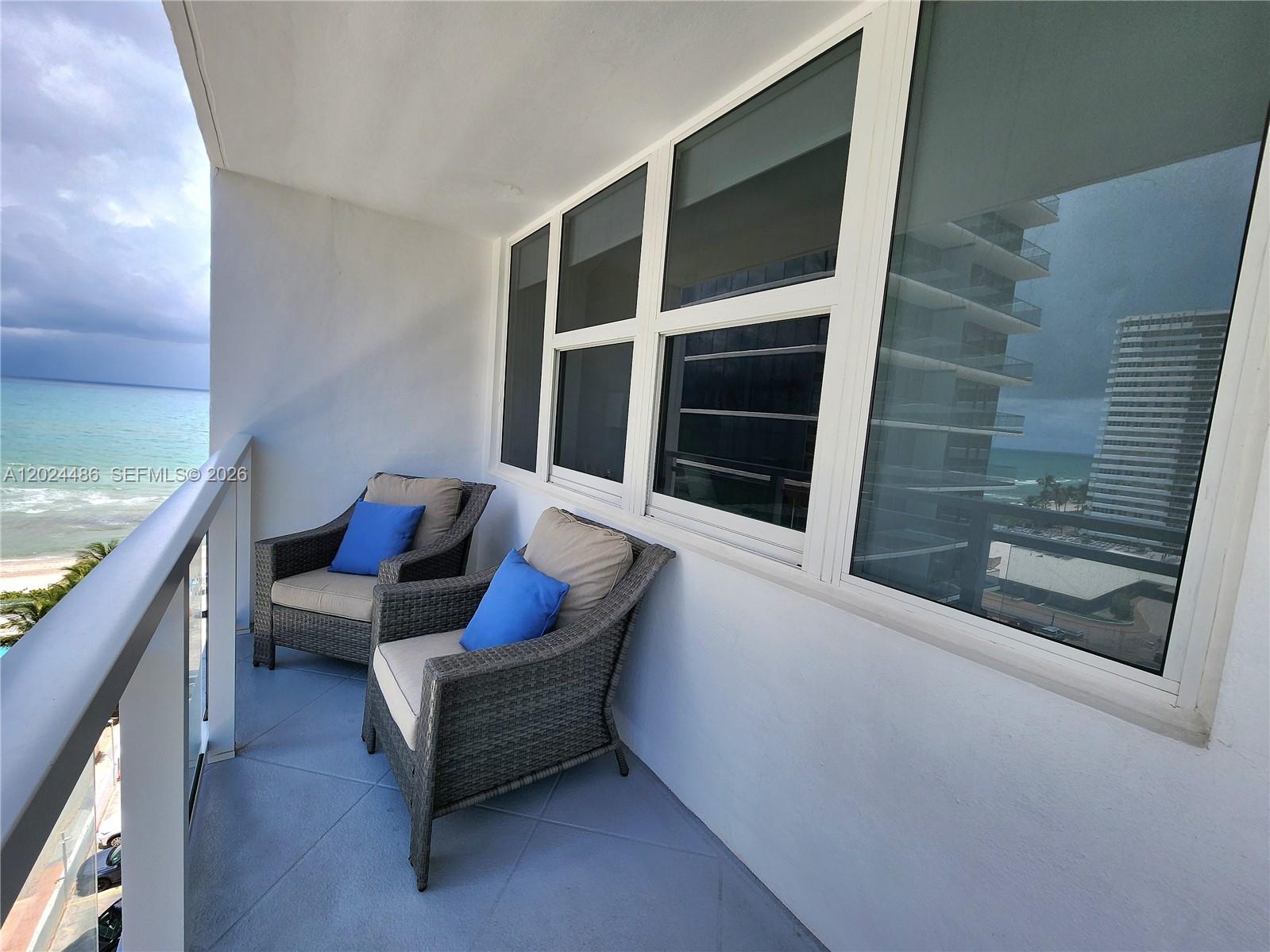 Two wicker chairs with blue pillows sit on a balcony overlooking the ocean — 2030 S Ocean Dr # 923, Hallandale Beach FL 33009, HALLANDALE BEACH, FL
