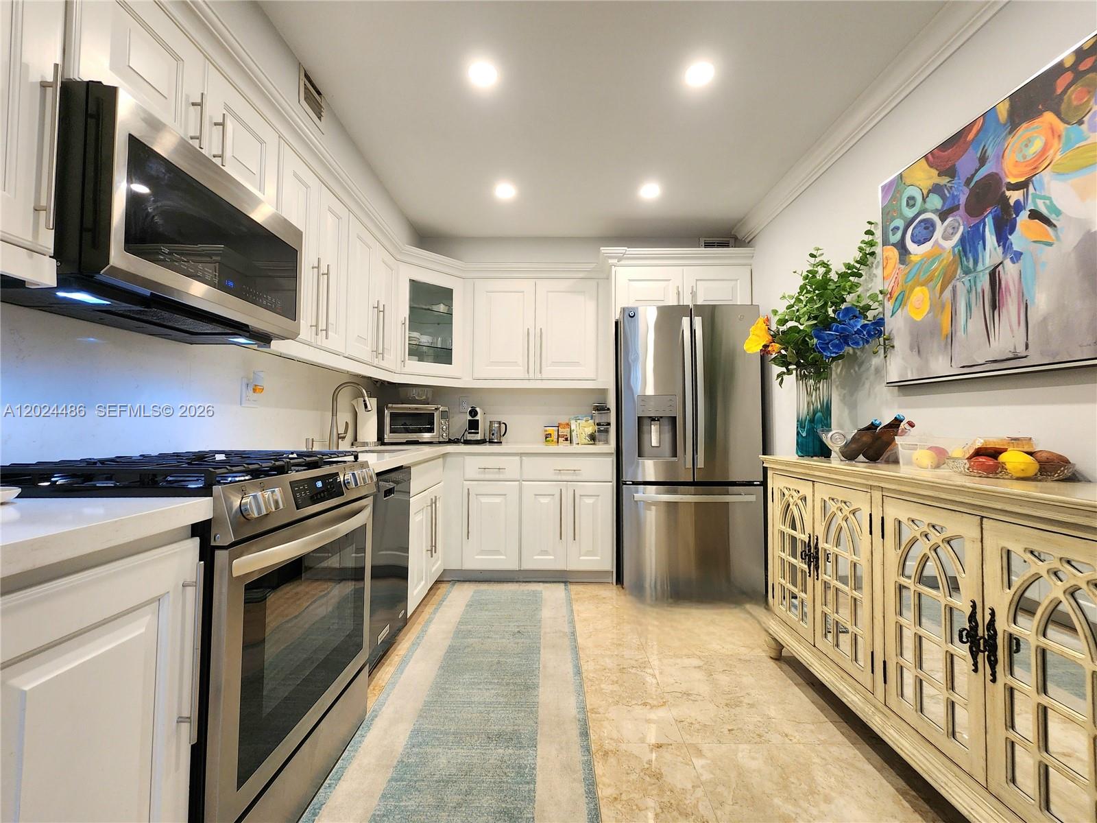A kitchen features white cabinetry, stainless steel appliances, a marble-tiled floor, and a decorative sideboard — 2030 S Ocean Dr # 923, Hallandale Beach FL 33009, HALLANDALE BEACH, FL