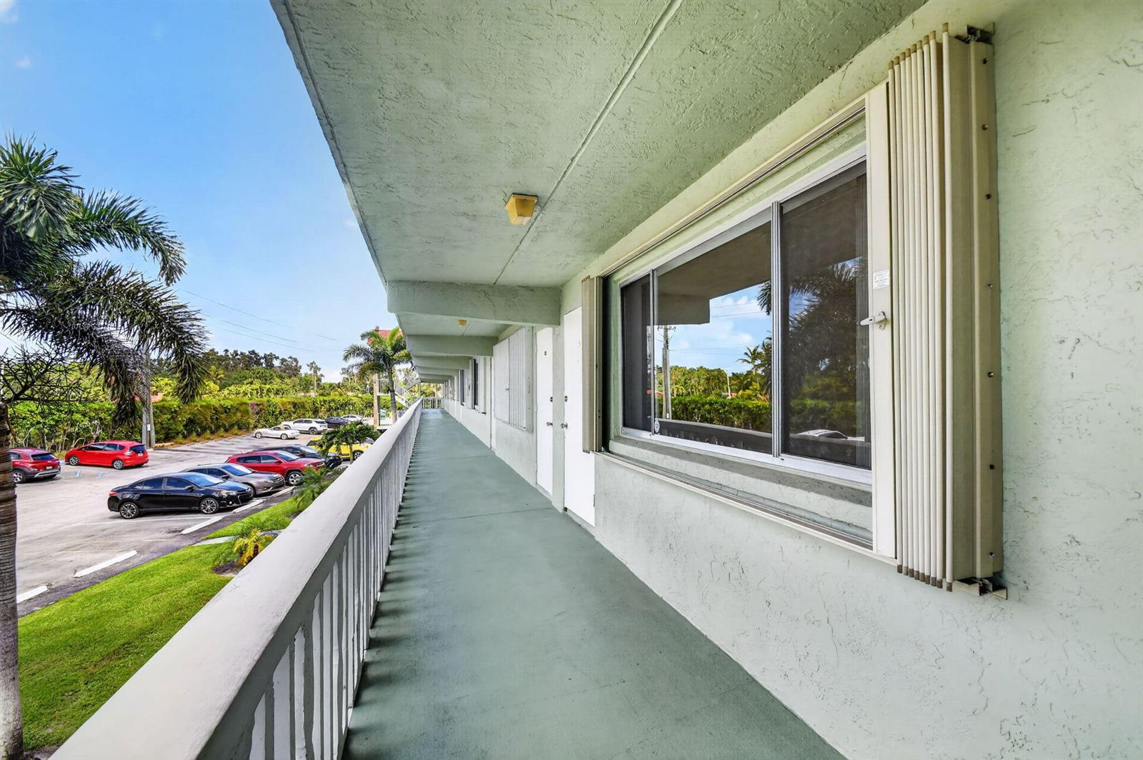 A three-story apartment building exterior features a red roof, white railings, and a palm tree — 3300 Springdale Boulevard # 208, Palm Springs FL 33461, PALM SPRINGS, FL