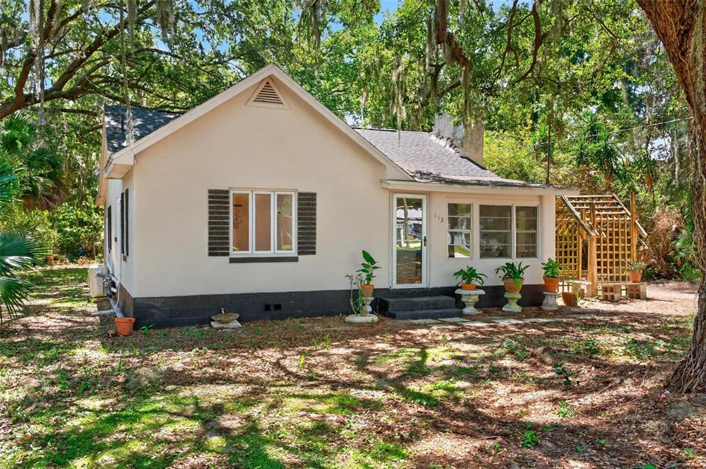A single-story house with a light-colored exterior, dark base, and a wooden trellis structure — 112 N LAKE AVENUE, LEESBURG, FL